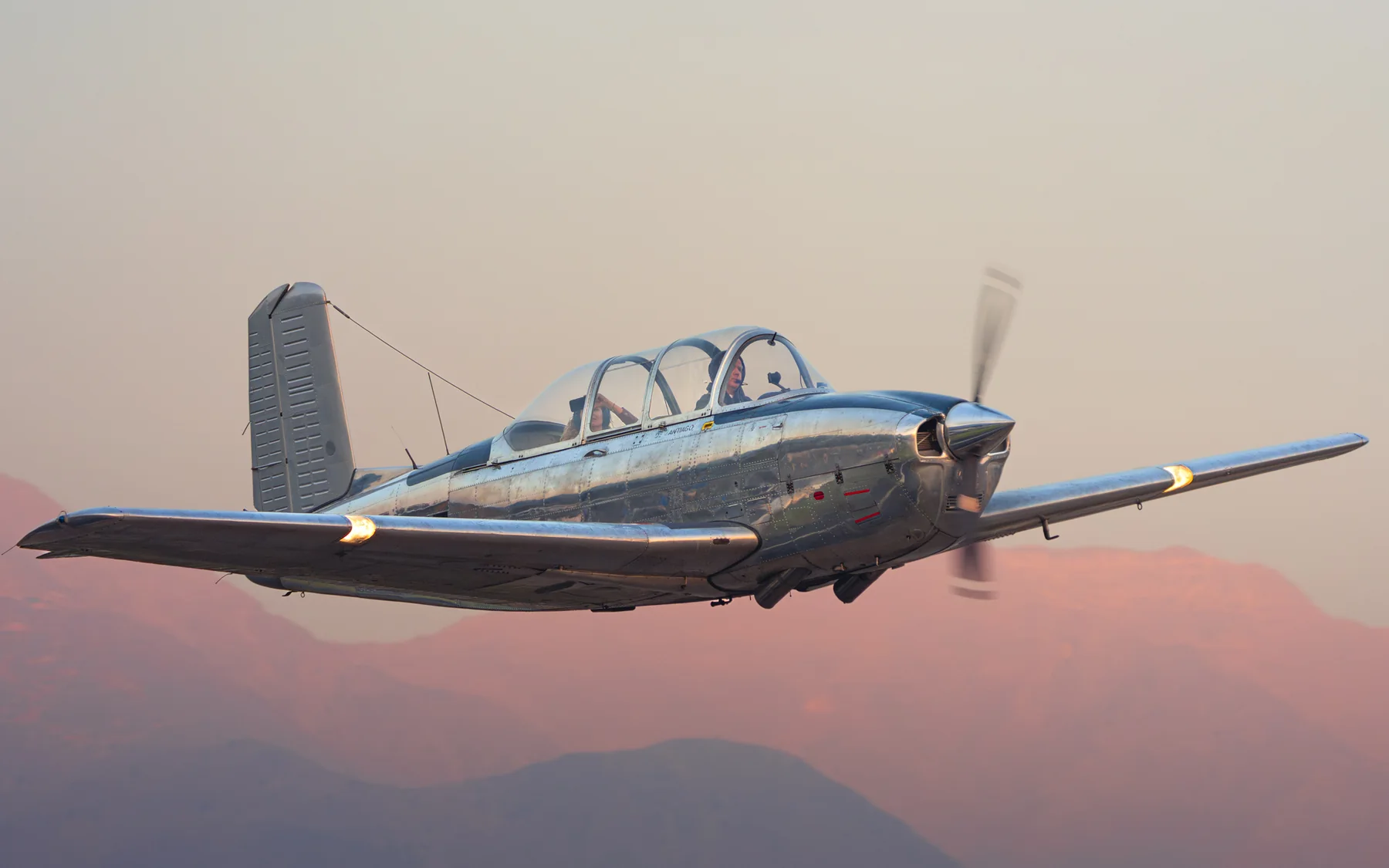 Avión clásico en vuelo frente a la cordillera
