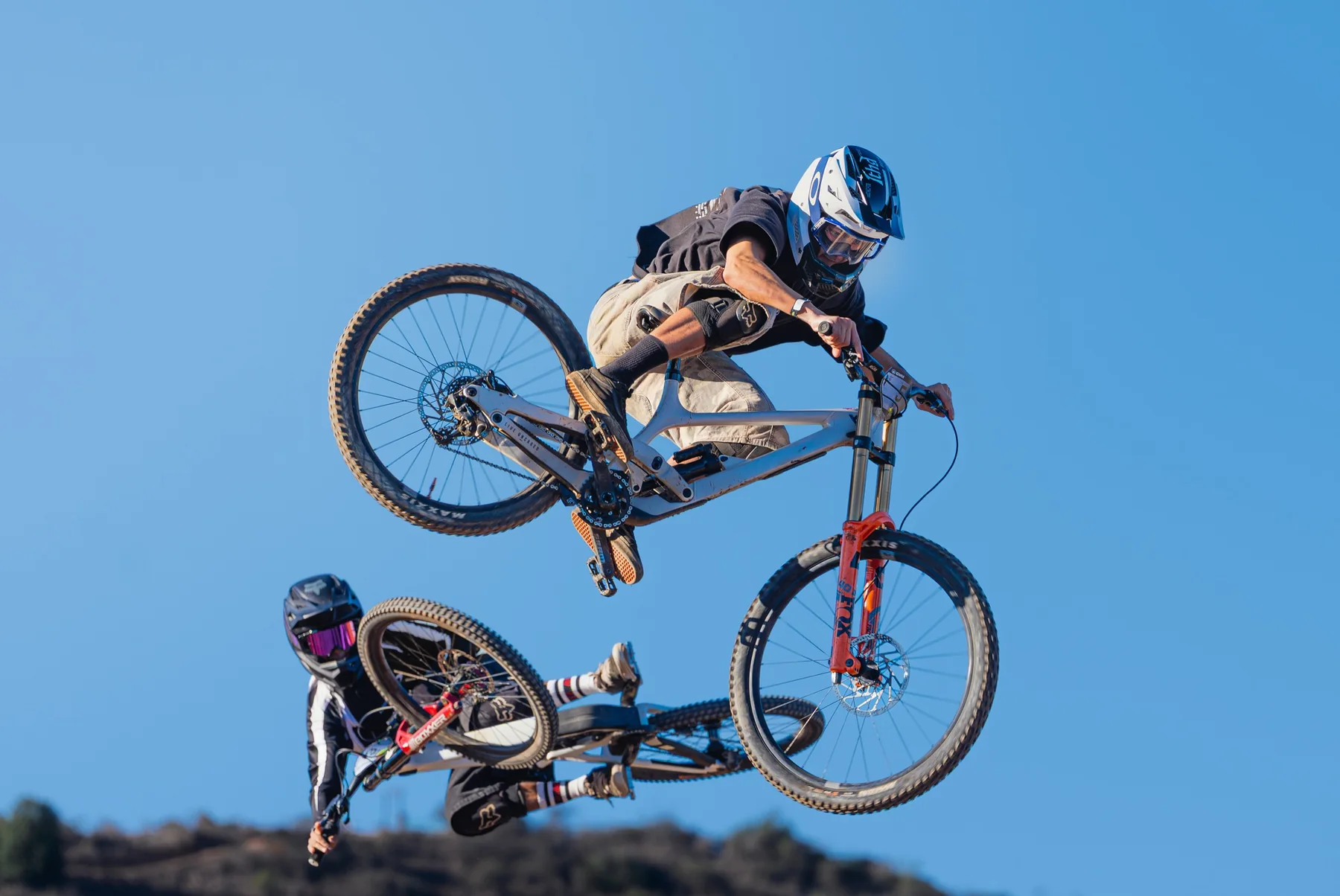 Dos ciclistas de downhill realizando saltos durante un evento deportivo